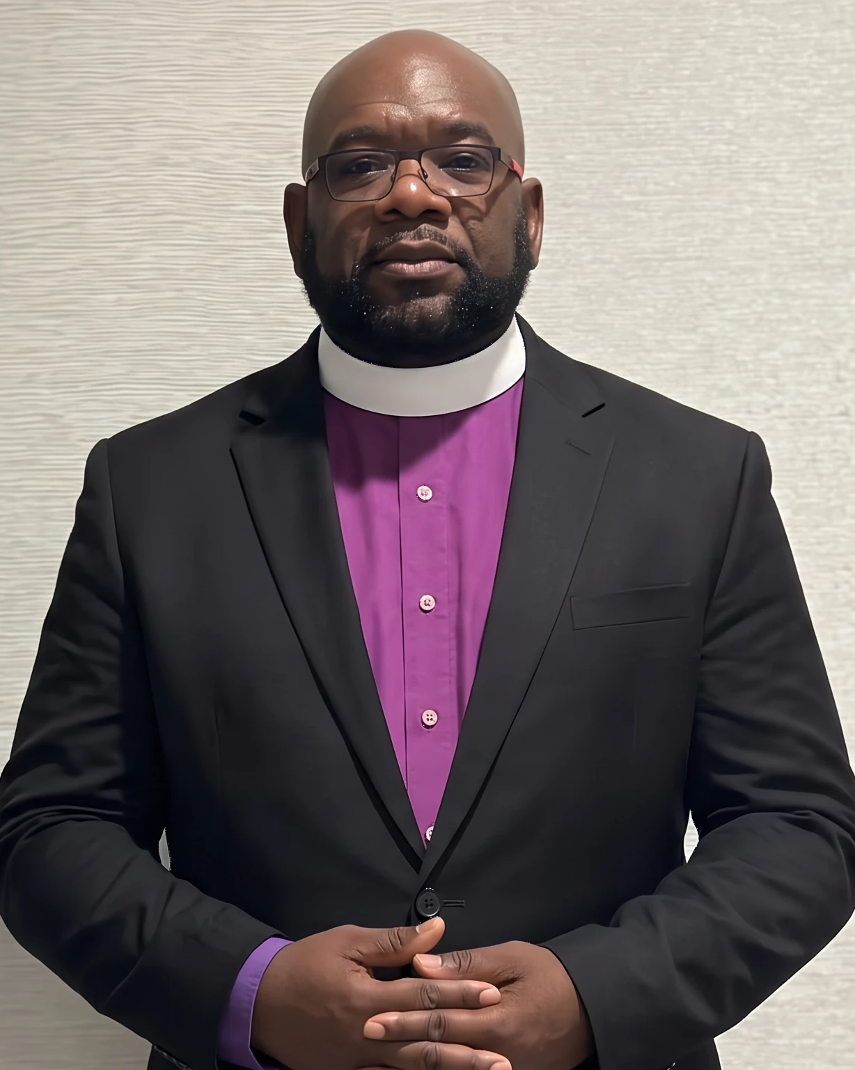 Bishop Jerome M. McLennon in a black suit, purple clergy shirt and white collar