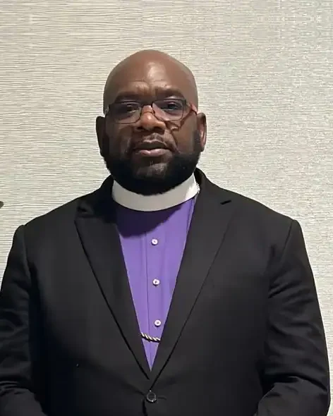 Bishop Jerome M. McLennon in a black suit, purple clergy shirt and white collar