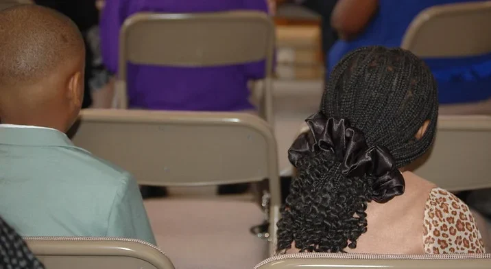 Two children sitting together during a service at Prayer Tower Church, seen from behind