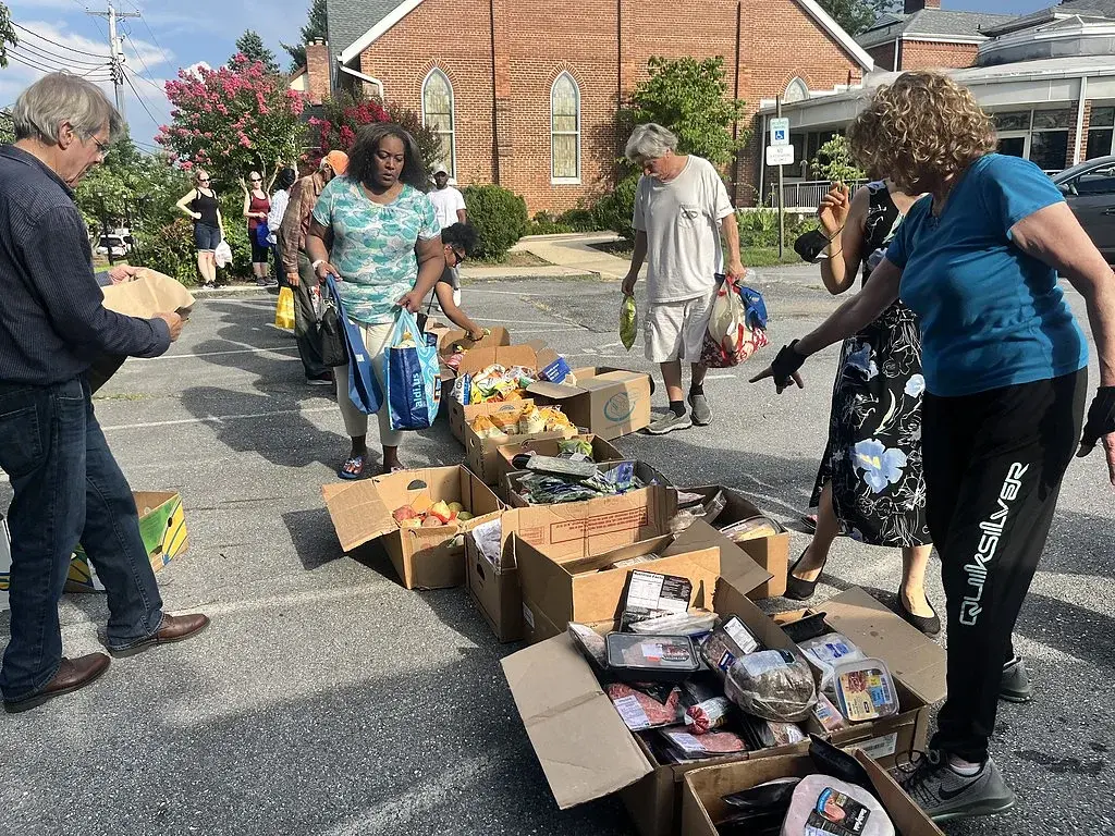 Volunteers and neighbors at a Prayer Tower Church food outreach in the parking lot, with the church building behind them